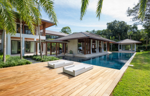 Garapa hardwood deck by luxury poolside home with palm trees